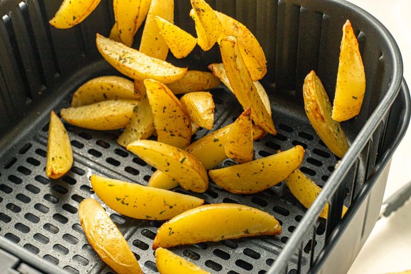 Potato wedges tossed in air fryer basket