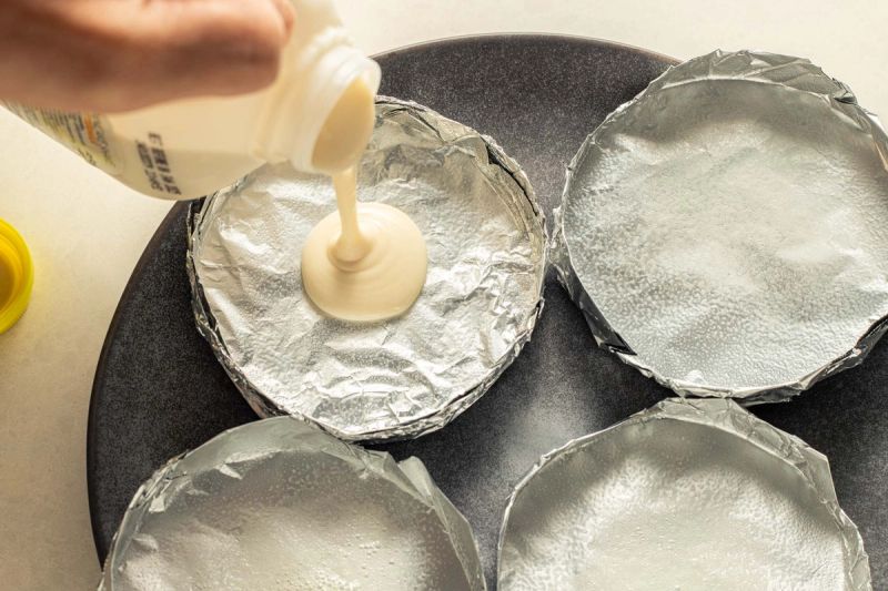 Pouring pancake batter into foil trays Pouring pancake batter into foil trays