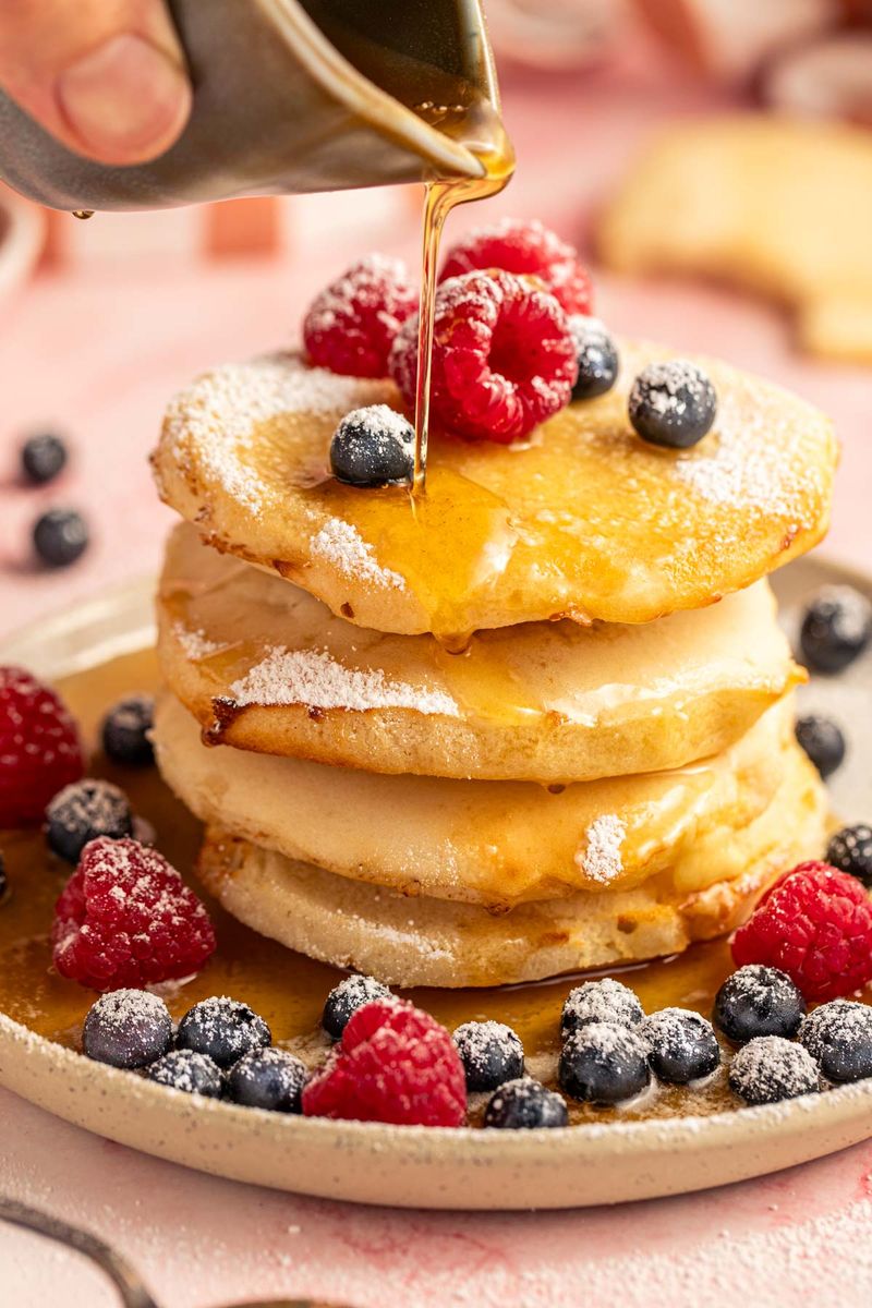 Maple syrup poured on a stack of pancakes with fresh berries Maple syrup poured on a stack of pancakes with fresh berries