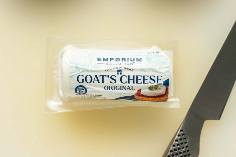 A goats cheese log in packaging on cutting board