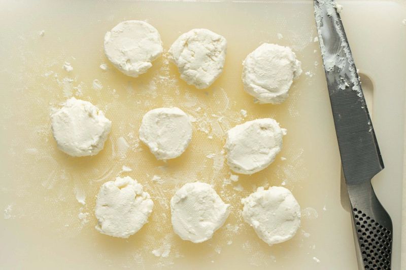 Sliced goats cheese on chopping board Sliced goats cheese on chopping board