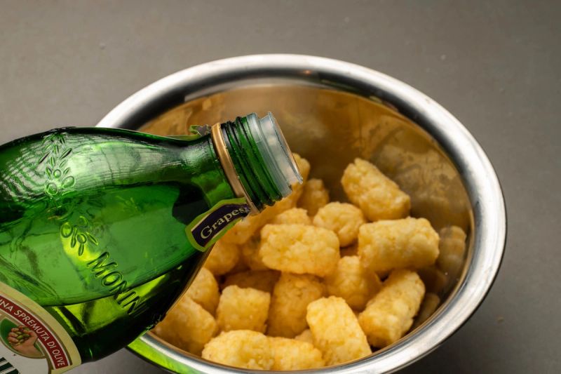 Pouring oil onto potato gems in a bowl