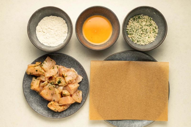 Preparing to coat chicken into flour, egg, then breadcrumbs Preparing to coat chicken into flour, egg, then breadcrumbs