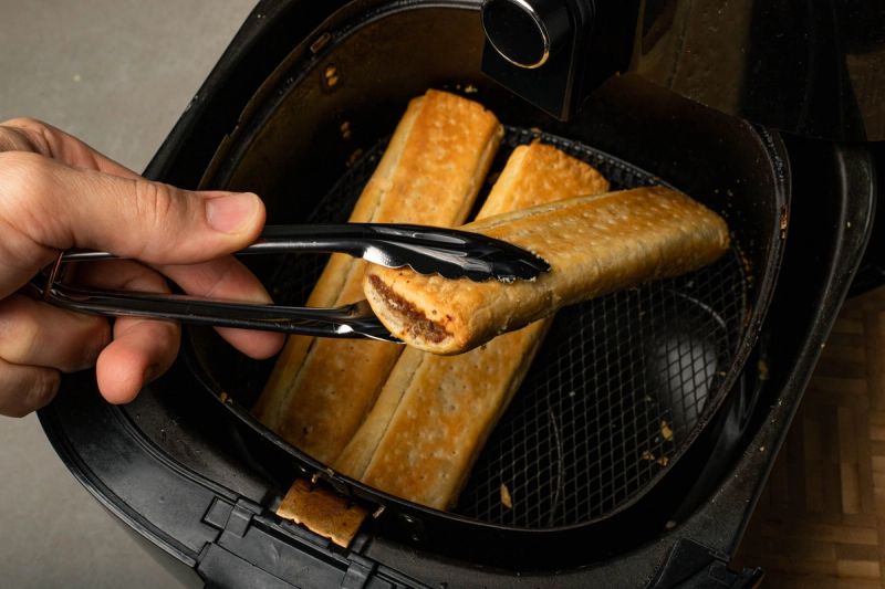 Flipping over a sausage roll in air fryer basket Flipping over a sausage roll in air fryer basket