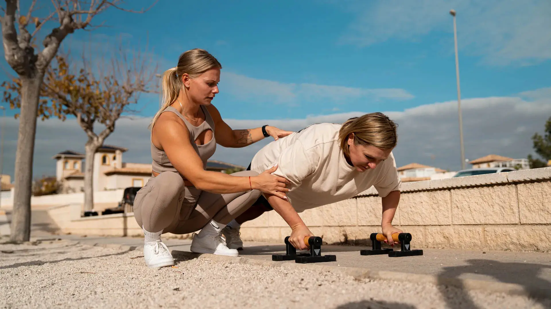 En kvinnlig calisthenics-coach hjälper sina klienter under träningen.