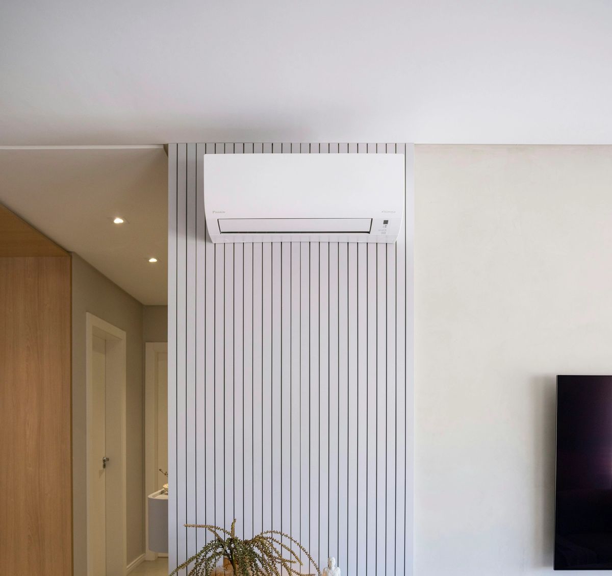 Split-system air conditioner mounted on a feature wall in a modern living room