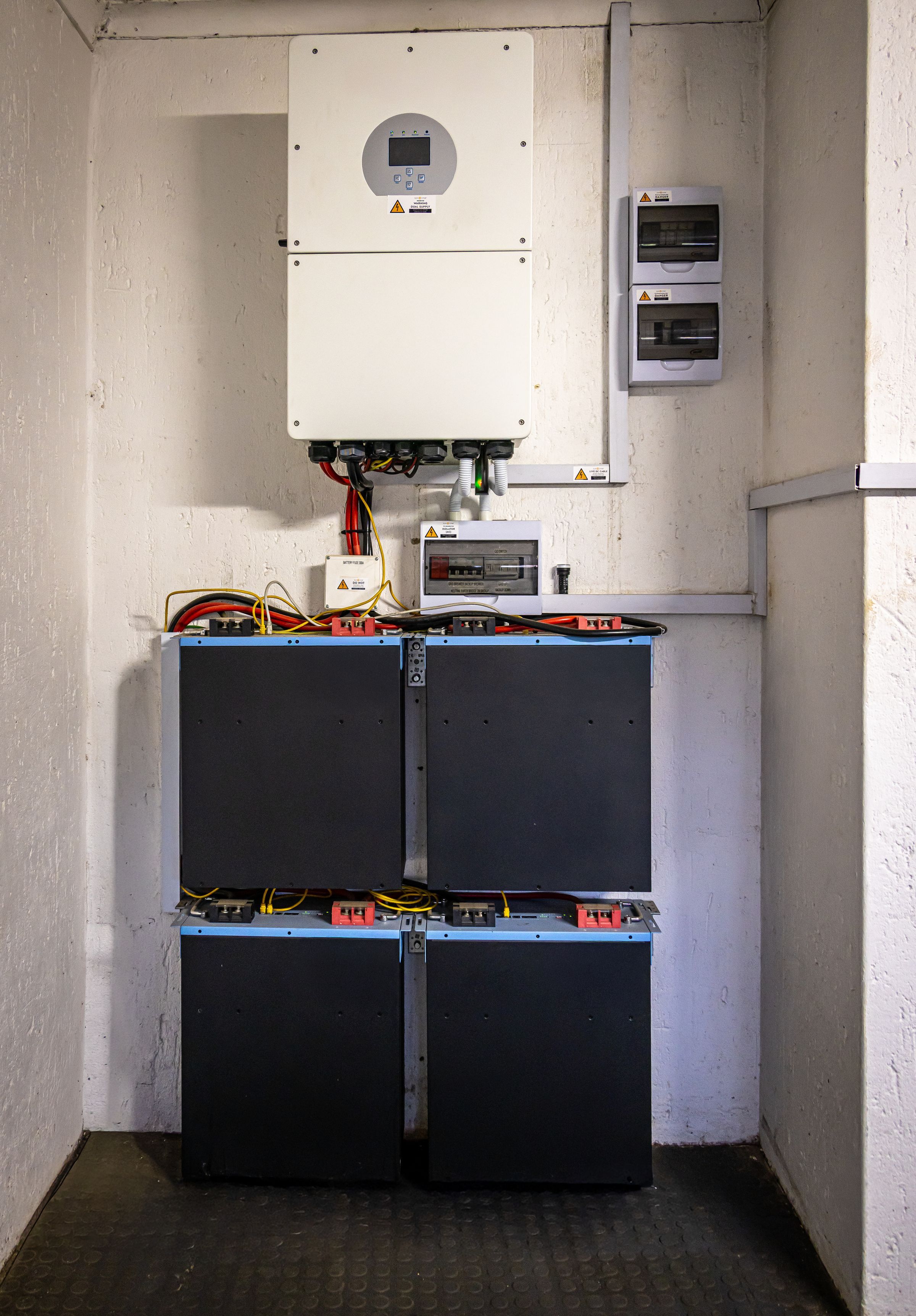 Home solar battery storage system with inverter installed on an interior wall