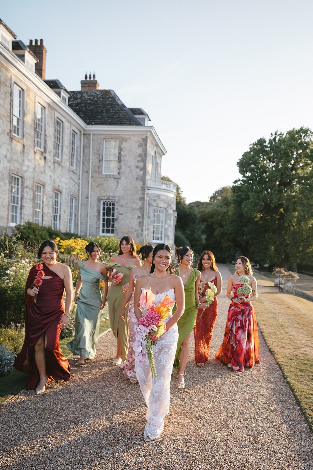 The bride carries a vibrant, flowing bridal bouquet featuring hot pink anthuriums, peach and yellow