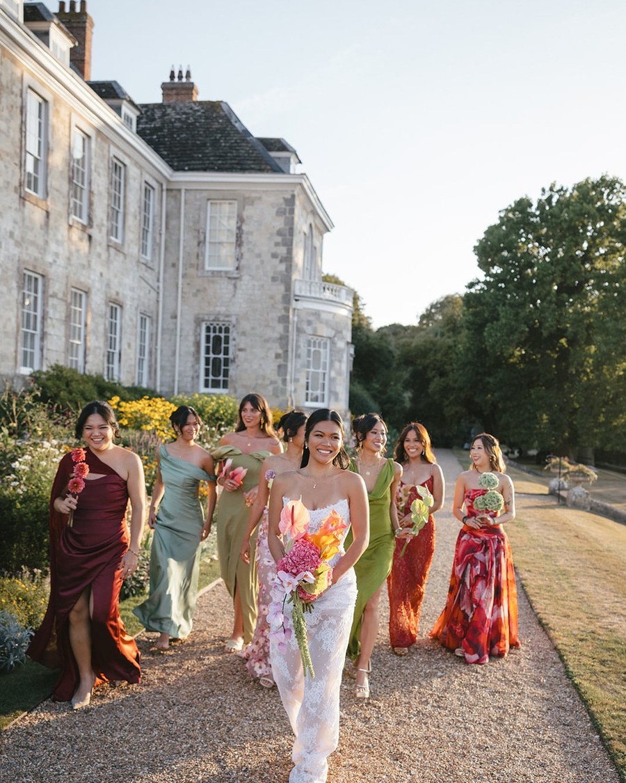 The bride carries a vibrant, flowing bridal bouquet featuring hot pink anthuriums, peach and yellow