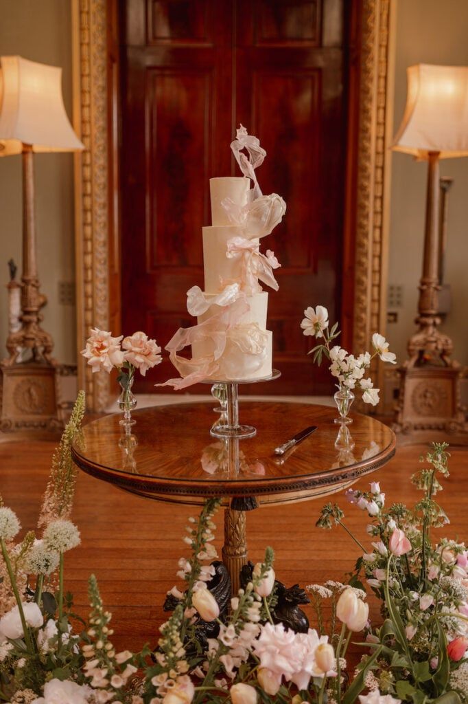 A three-tier, round cake covered in smooth, pale ivory buttercream, featuring delicate, ethereal