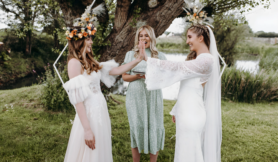 An outdoor ceremony taking place by a small body of water, possibly a pond or stream, with two