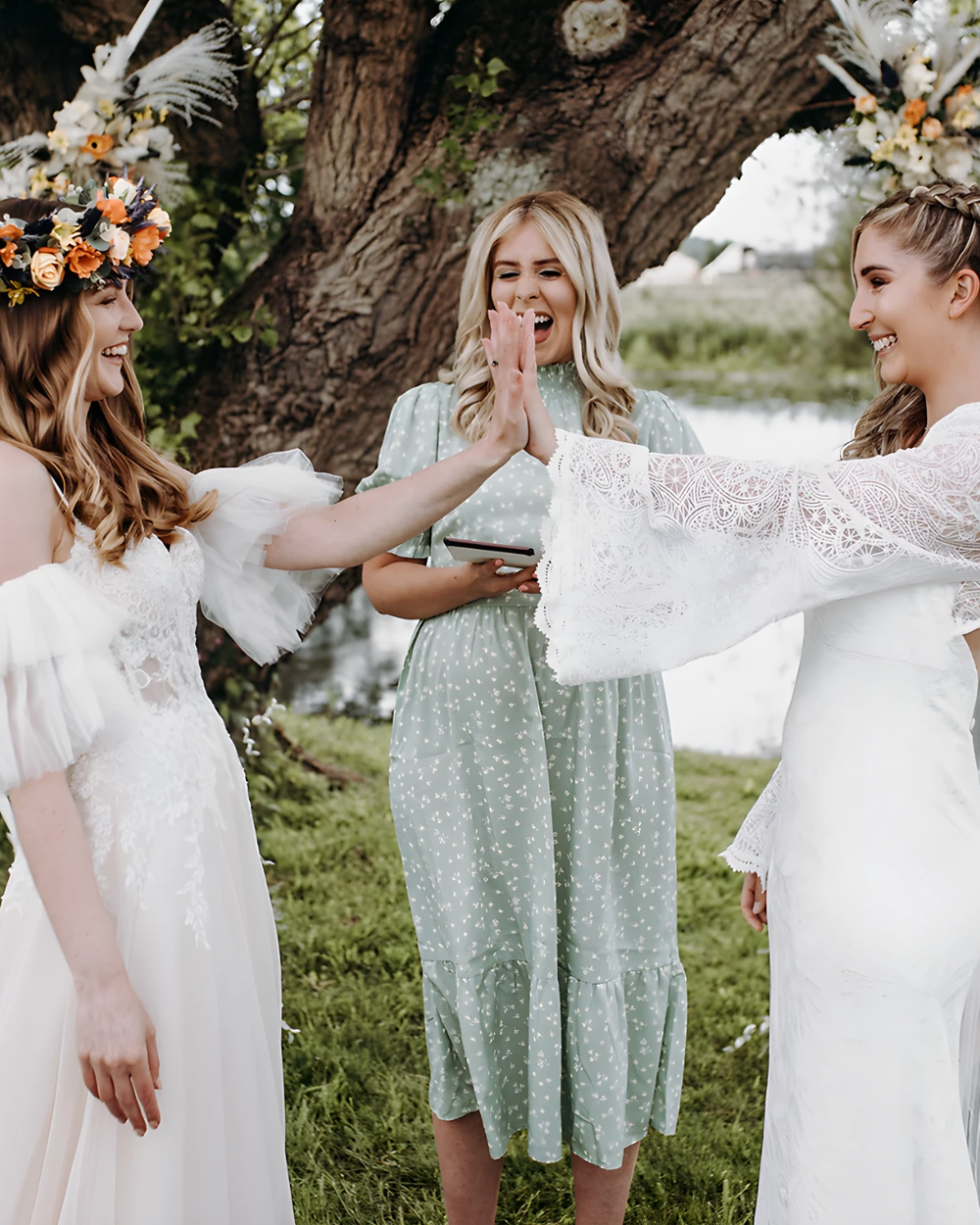 An outdoor ceremony taking place by a small body of water, possibly a pond or stream, with two