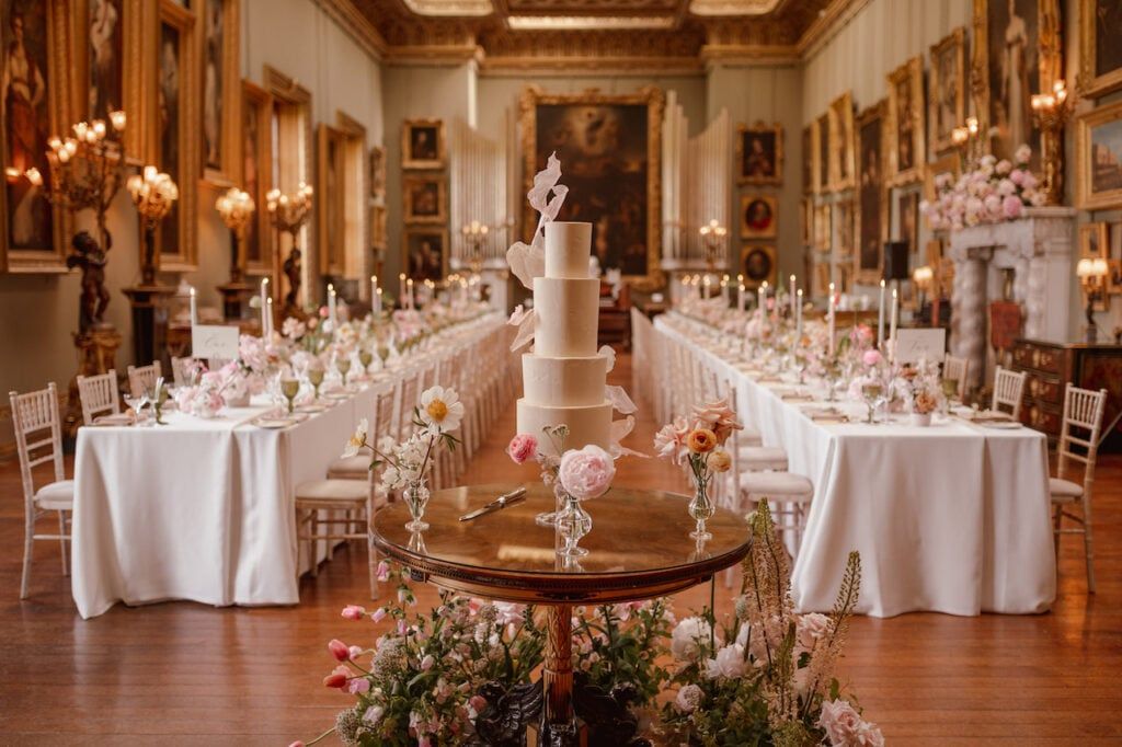 A four-tier round cake with a smooth, light ivory surface finish, featuring delicate, irregular