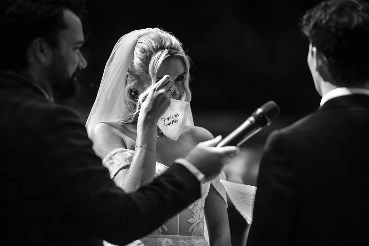 A bride wipes away tears with a handkerchief printed with "keep your shit together" during a