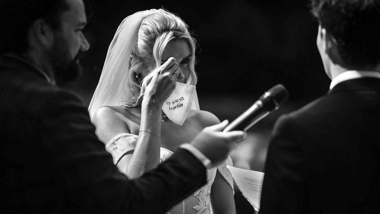 A bride wipes away tears with a handkerchief printed with "keep your shit together" during a