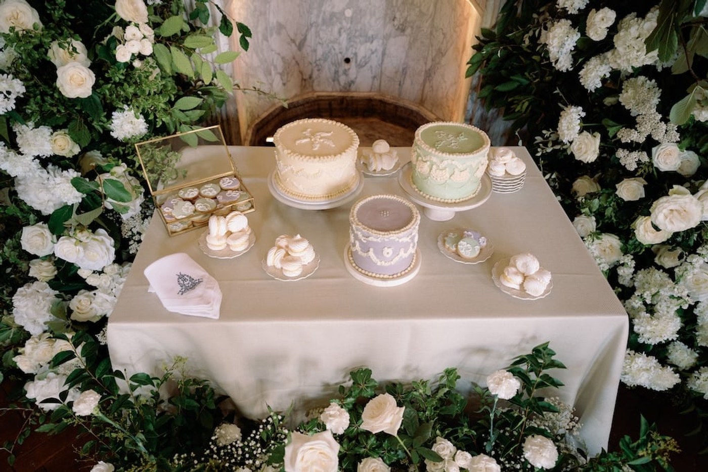 A dessert table featuring three single-tier round cakes in pastel colours, alongside various sweet