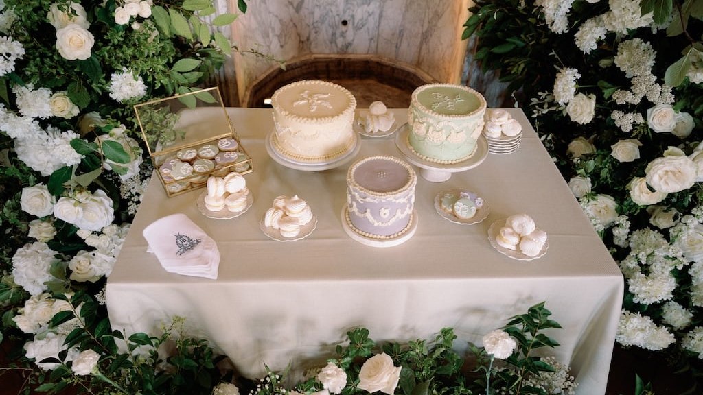 A dessert table featuring three single-tier round cakes in pastel colours, alongside various sweet