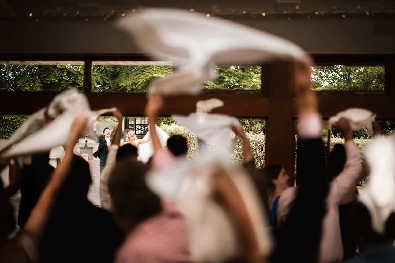 The newly married couple reacts with open-mouthed joy as they are welcomed into a reception room
