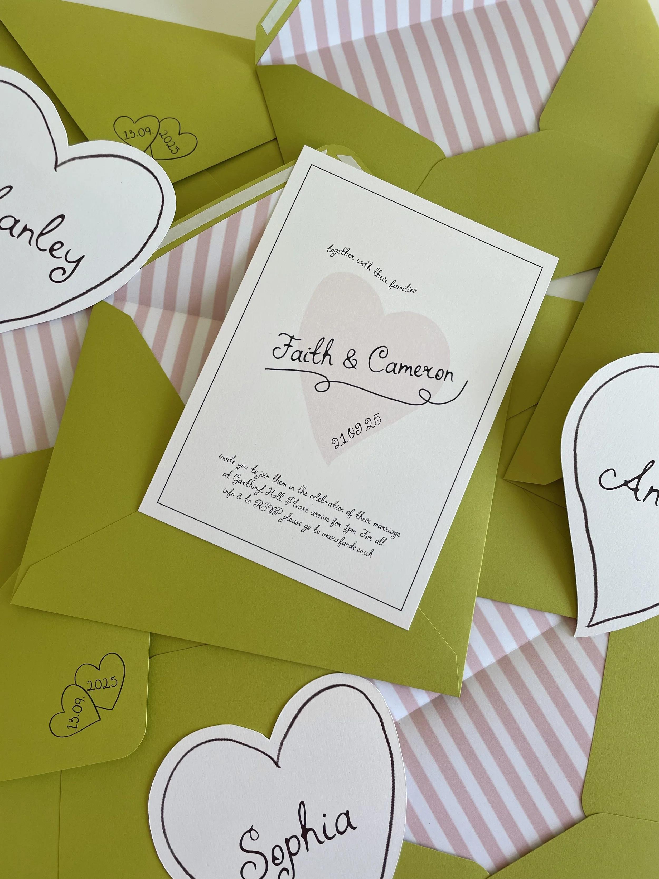 A playful and whimsical invitation suite featuring a central invitation with a delicate pink heart