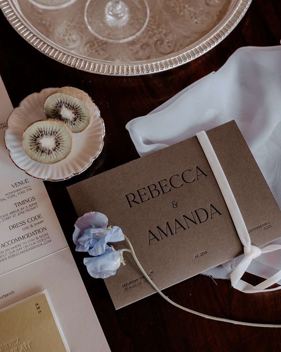 A rustic invitation suite featuring a brown card with embossed sans-serif typography for the