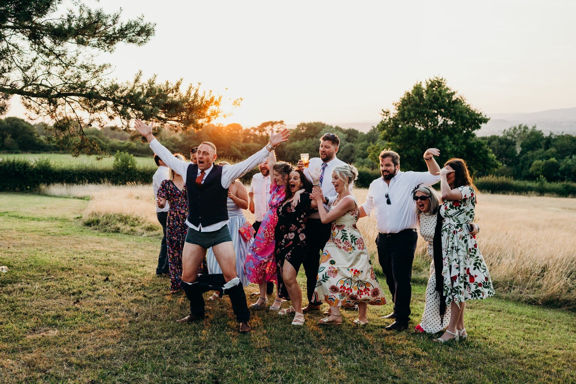 A group of wedding guests, including one man with his trousers around his ankles revealing striped