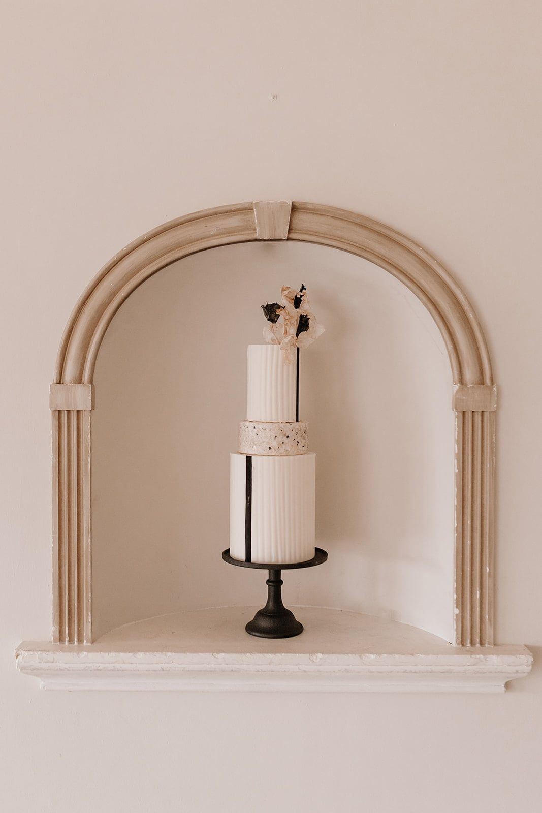 A three-tier round cake featuring a minimalist modern design with clean lines. The top and bottom
