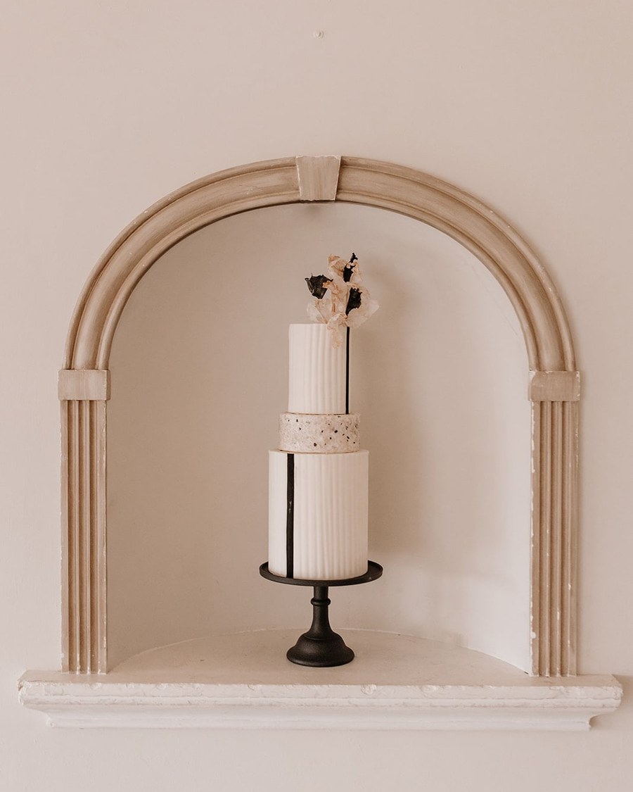 A three-tier round cake featuring a minimalist modern design with clean lines. The top and bottom