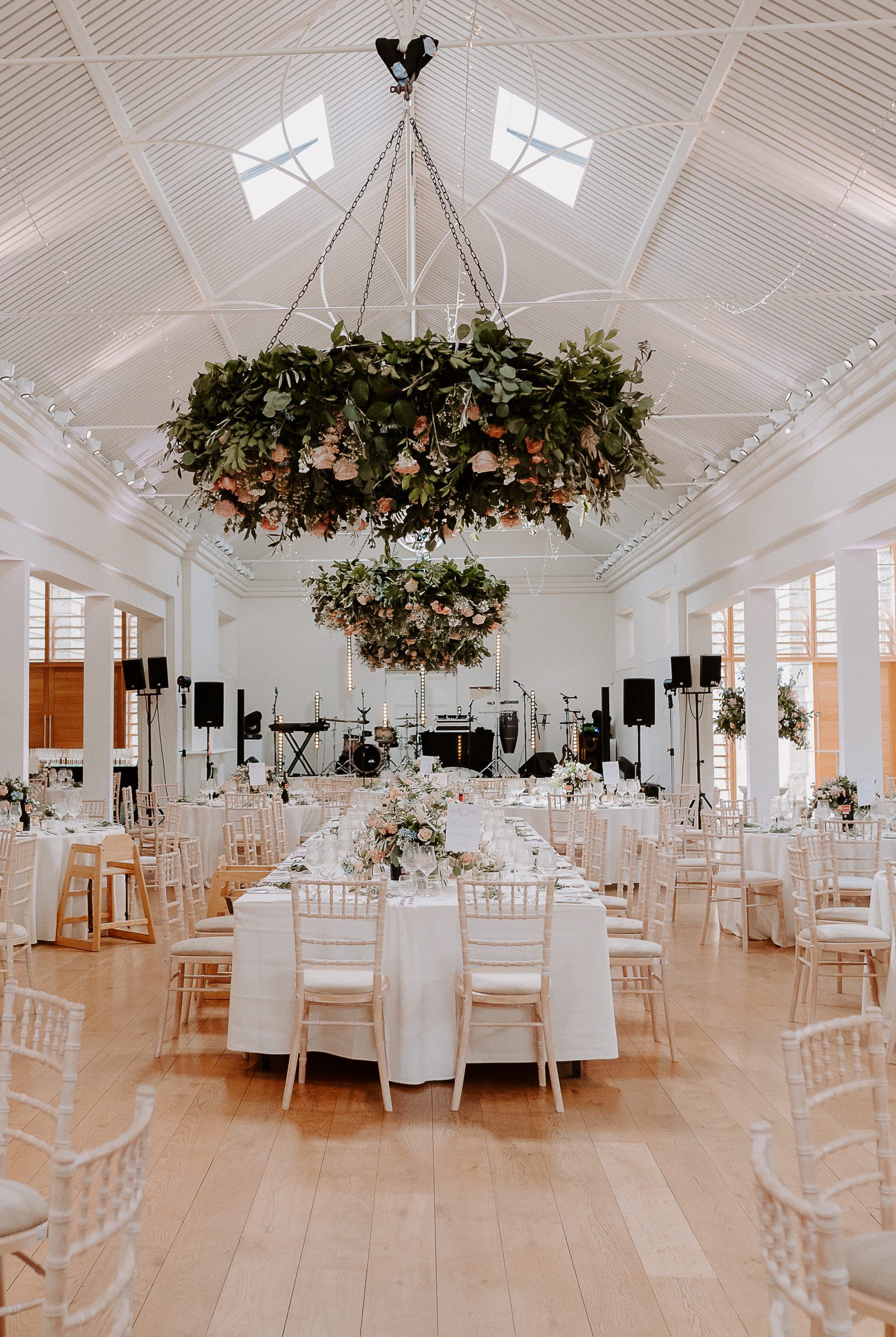 A wide shot of a wedding reception set up in a bright, modern hall with high white ceilings and