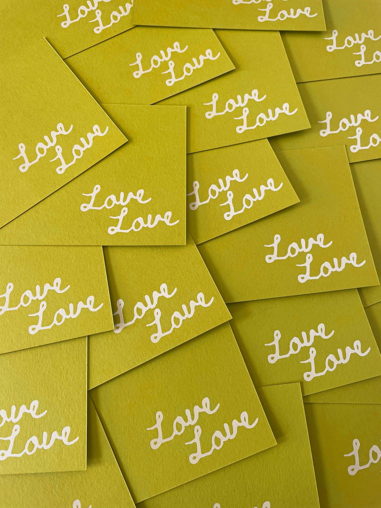 A playful collection of green cards, possibly place cards, with the word 'Love' repeatedly