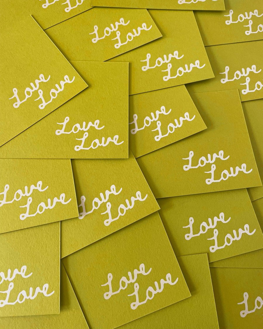 A playful collection of green cards, possibly place cards, with the word 'Love' repeatedly