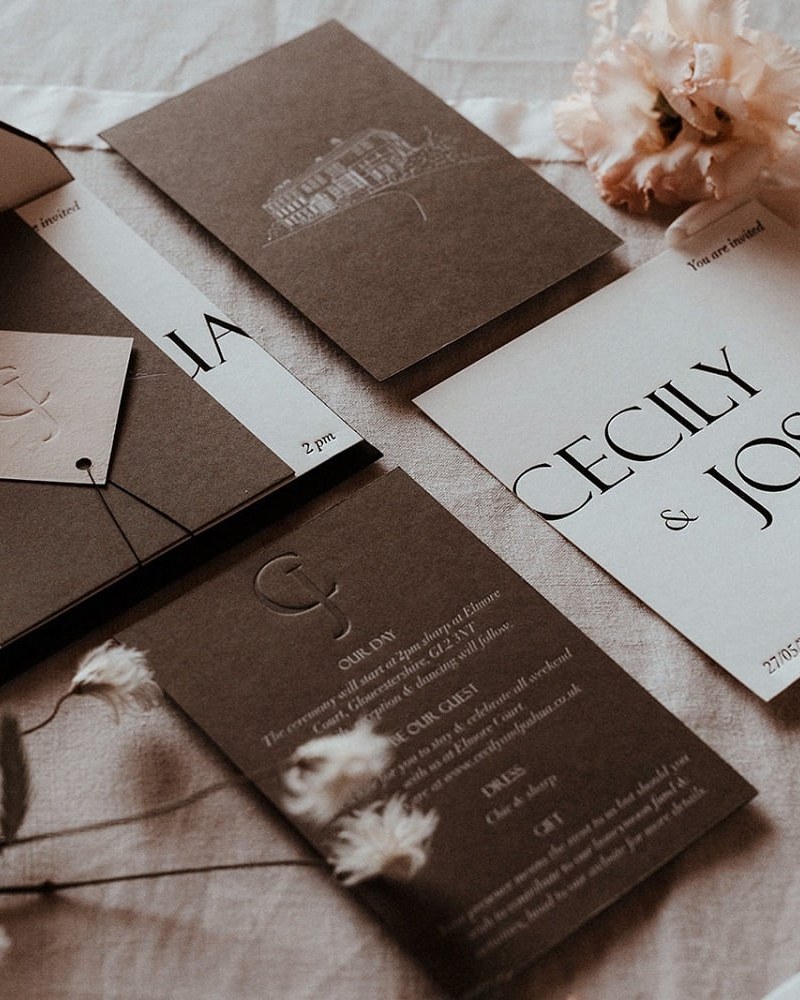 A sophisticated stationery suite on dark stock and white card, featuring a mix of modern serif and