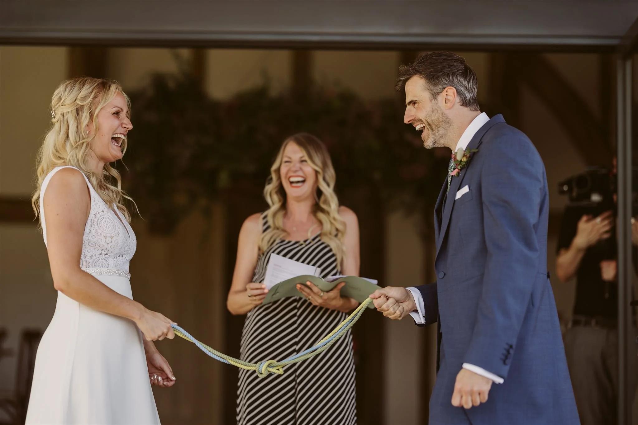A close-up of a celebrant, couple, and a handfasting cord, captured during a ceremony. All three