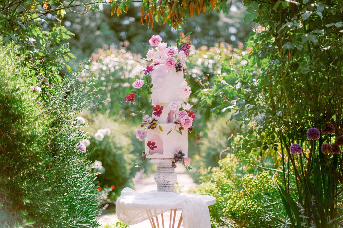 A three-tier, square cake with an off-white, slightly textured surface, possibly semi-naked or