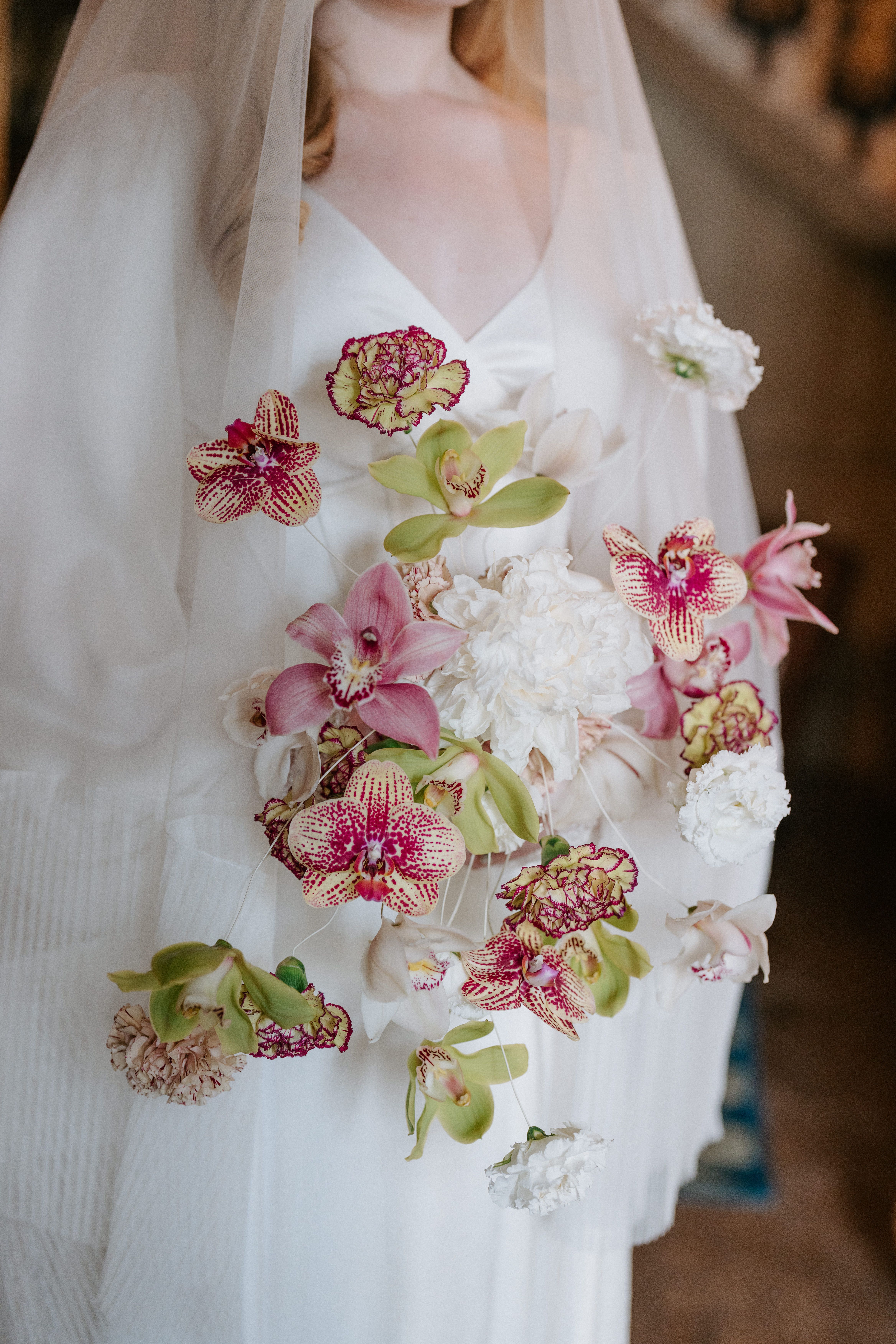 A close-up of a bride holding a contemporary deconstructed bouquet featuring individual blooms of