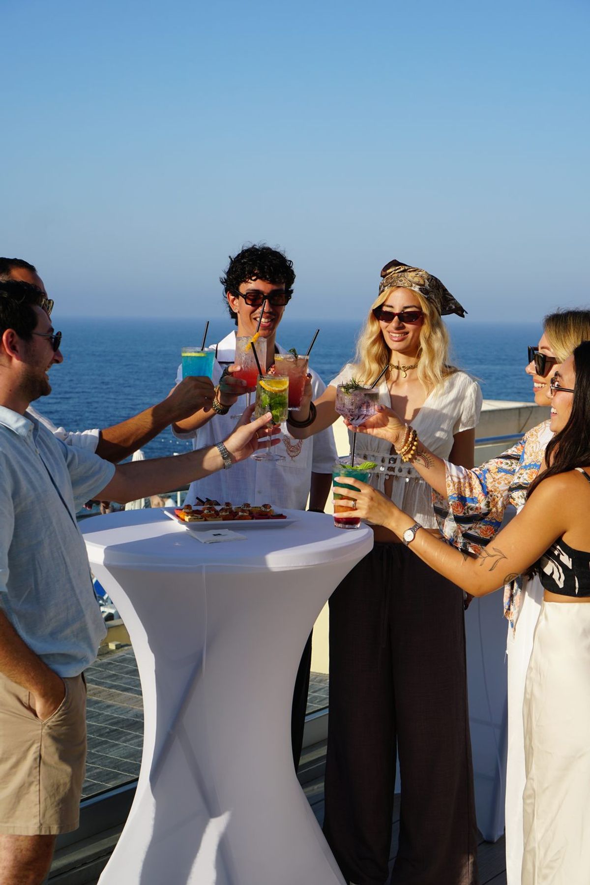 A group cheersing with cocktails against a sea view