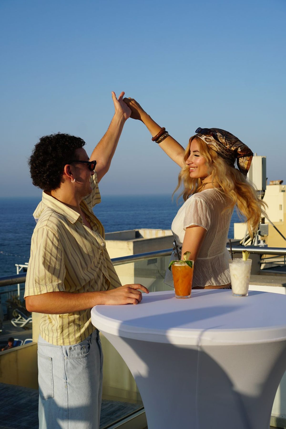 Two people celebrating with cocktails at a rooftop bar