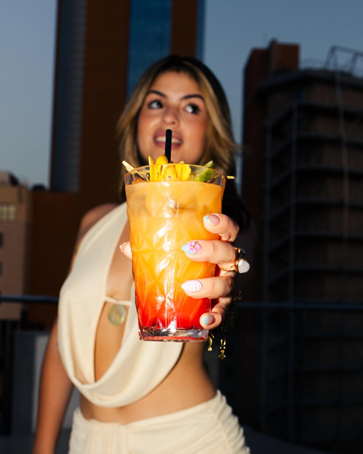 Two people celebrating with cocktails at a rooftop bar