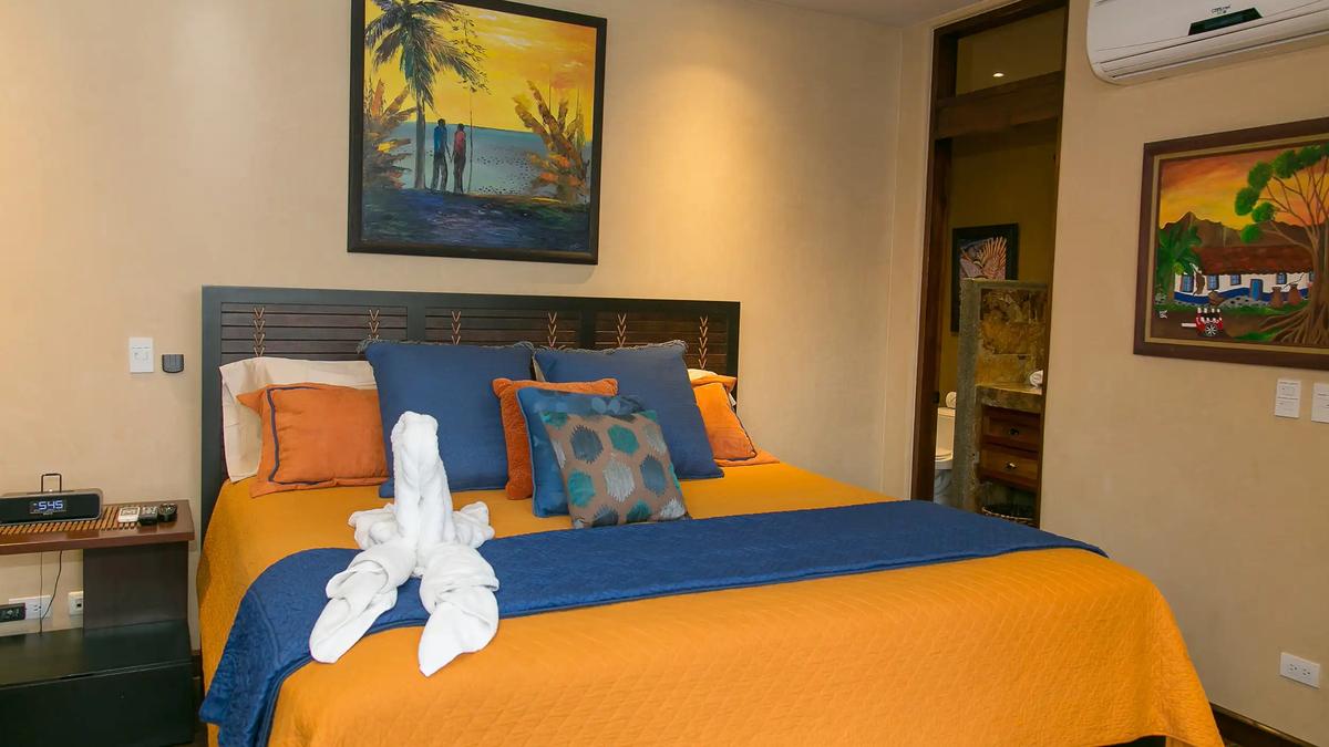 Bedroom with orange and blue bedding and tropical artwork at Casa Anaka