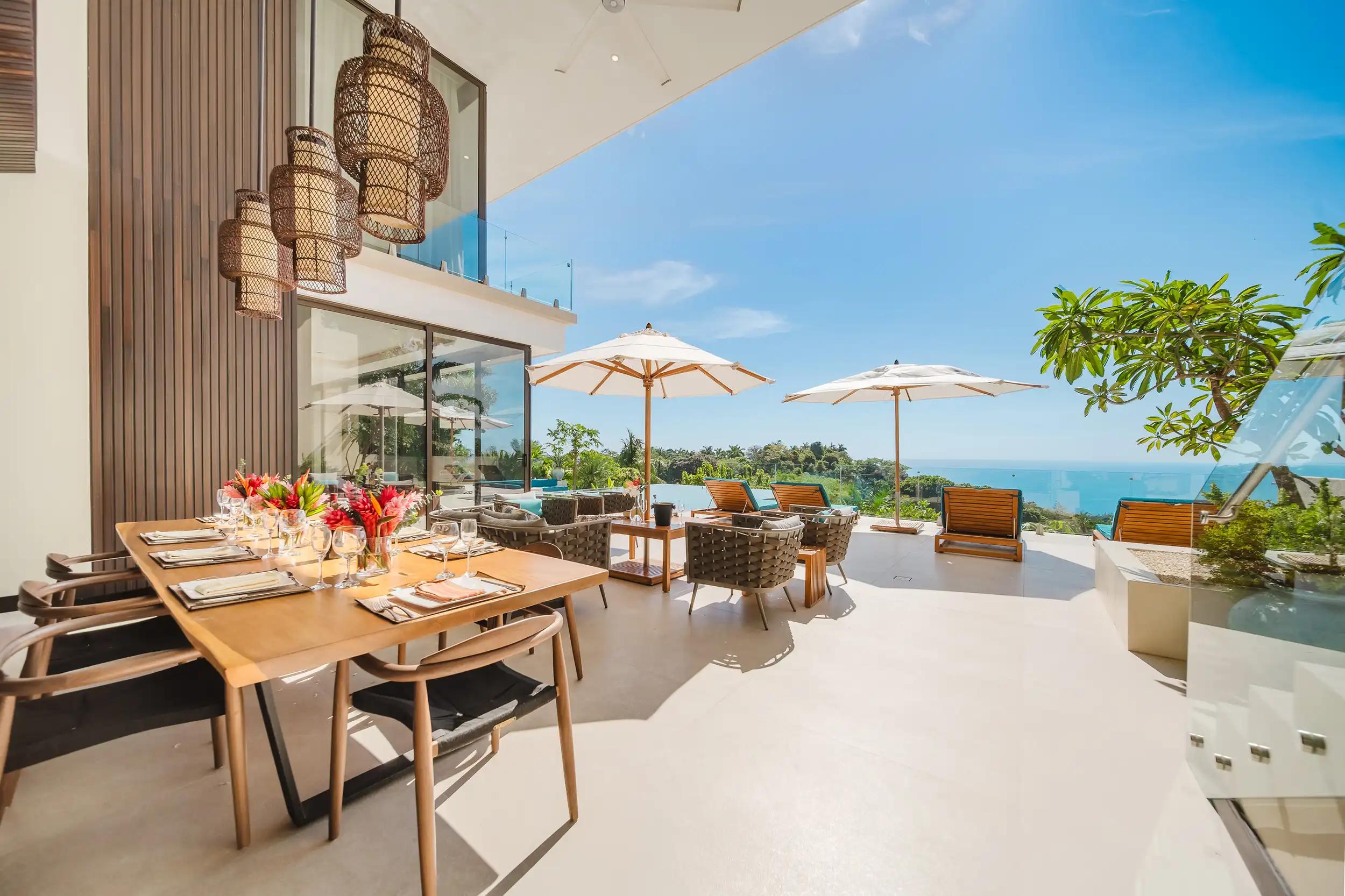 Casa Nola terrace with outdoor dining table, umbrellas, and lounge seating above the Pacific