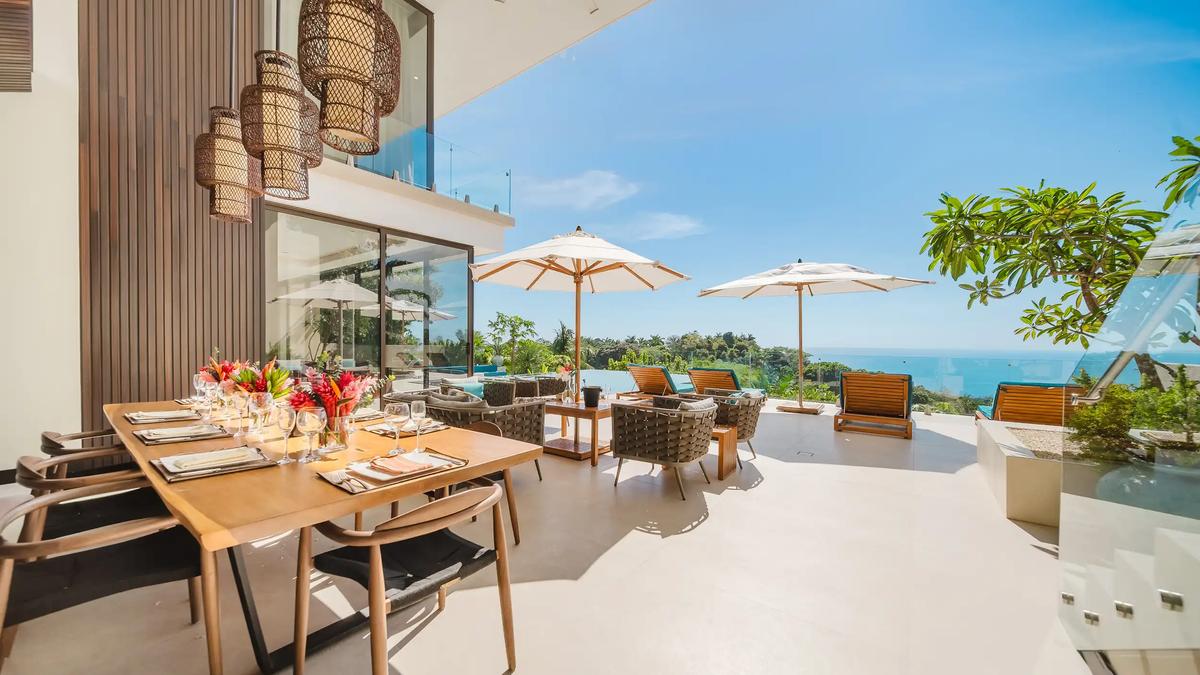 Casa Nola terrace with outdoor dining table, umbrellas, and lounge seating above the Pacific