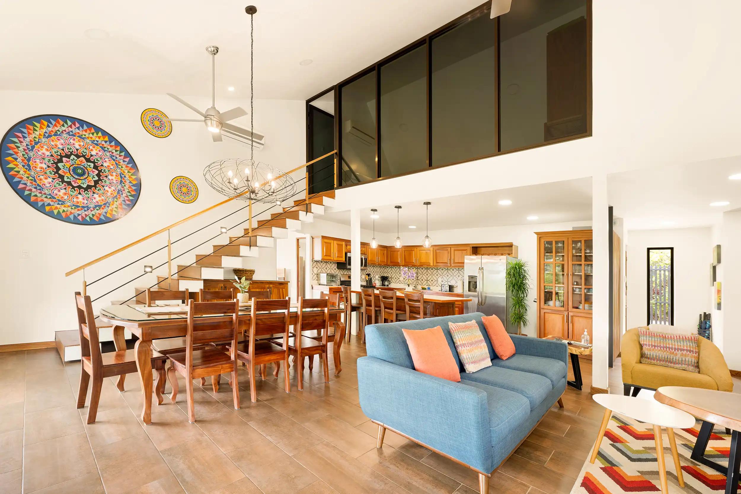 Casa Vista Verde living area with blue sofa, dining table, and colorful oxcart wheel art