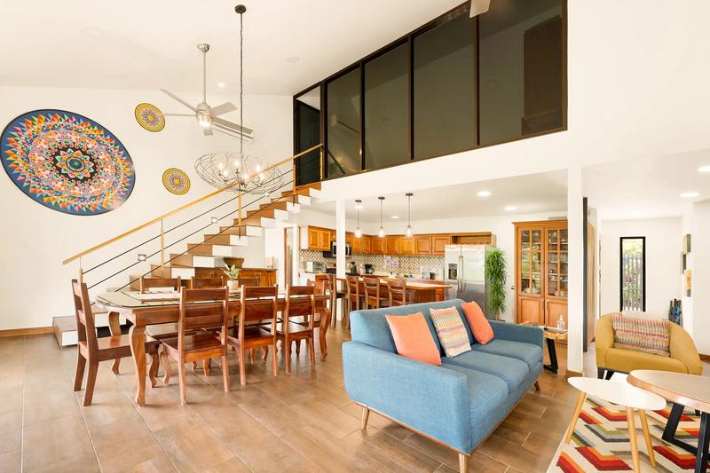 Casa Vista Verde living area with blue sofa, dining table, and colorful oxcart wheel art