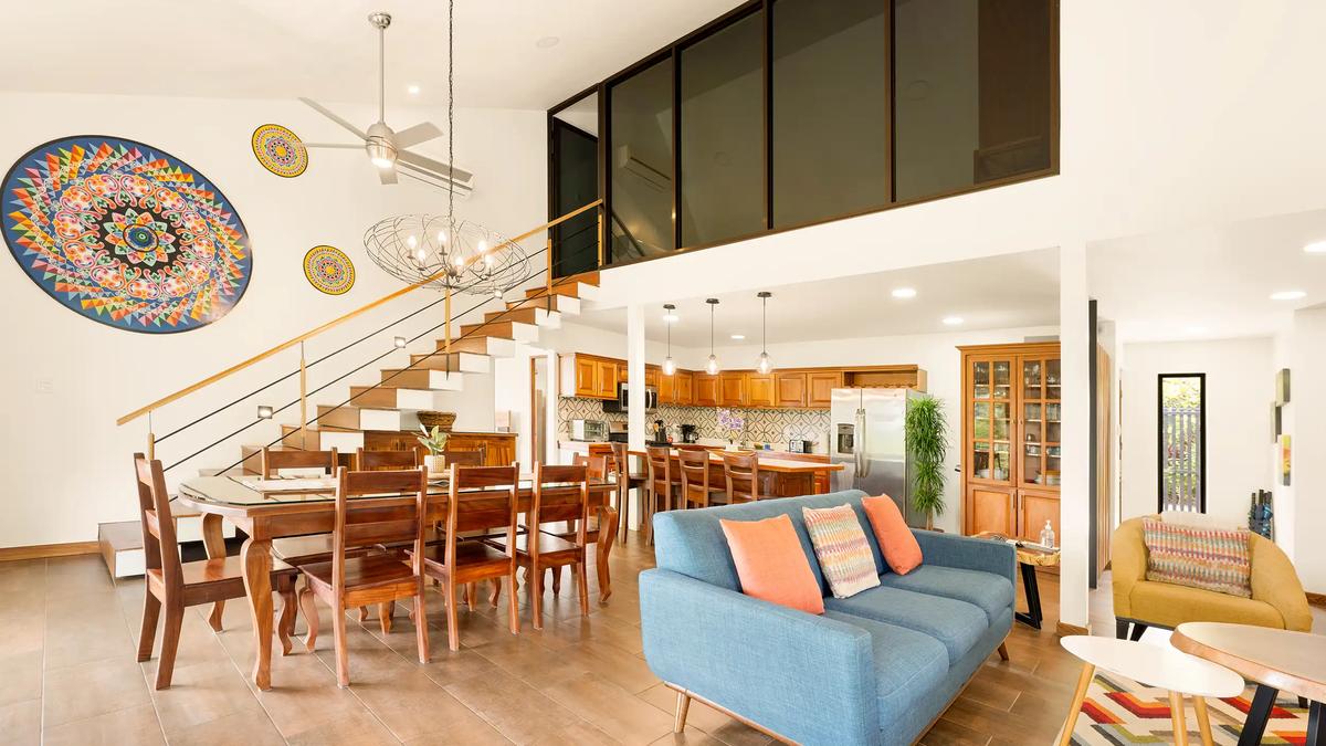 Casa Vista Verde living area with blue sofa, dining table, and colorful oxcart wheel art
