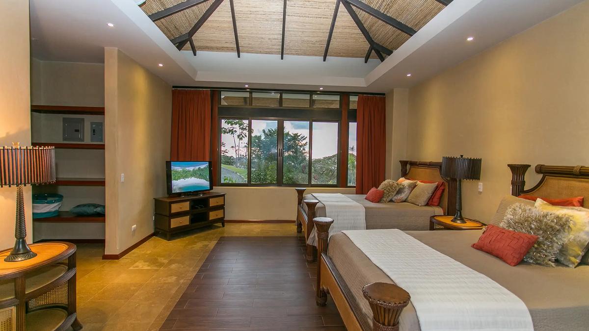 Two queen beds, TV, and built-in shelves in the vaulted bedroom at Casa Anaka
