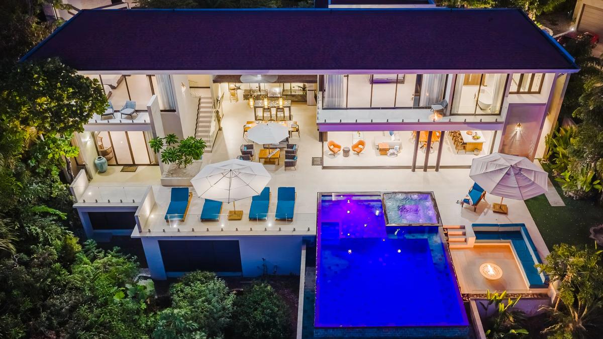 Night aerial of Casa Nola, the infinity pool lit blue among the trees