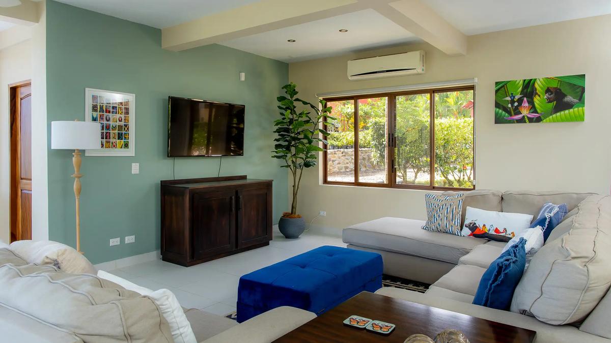TV lounge at Casa Mariposa with sectional seating and a garden view window