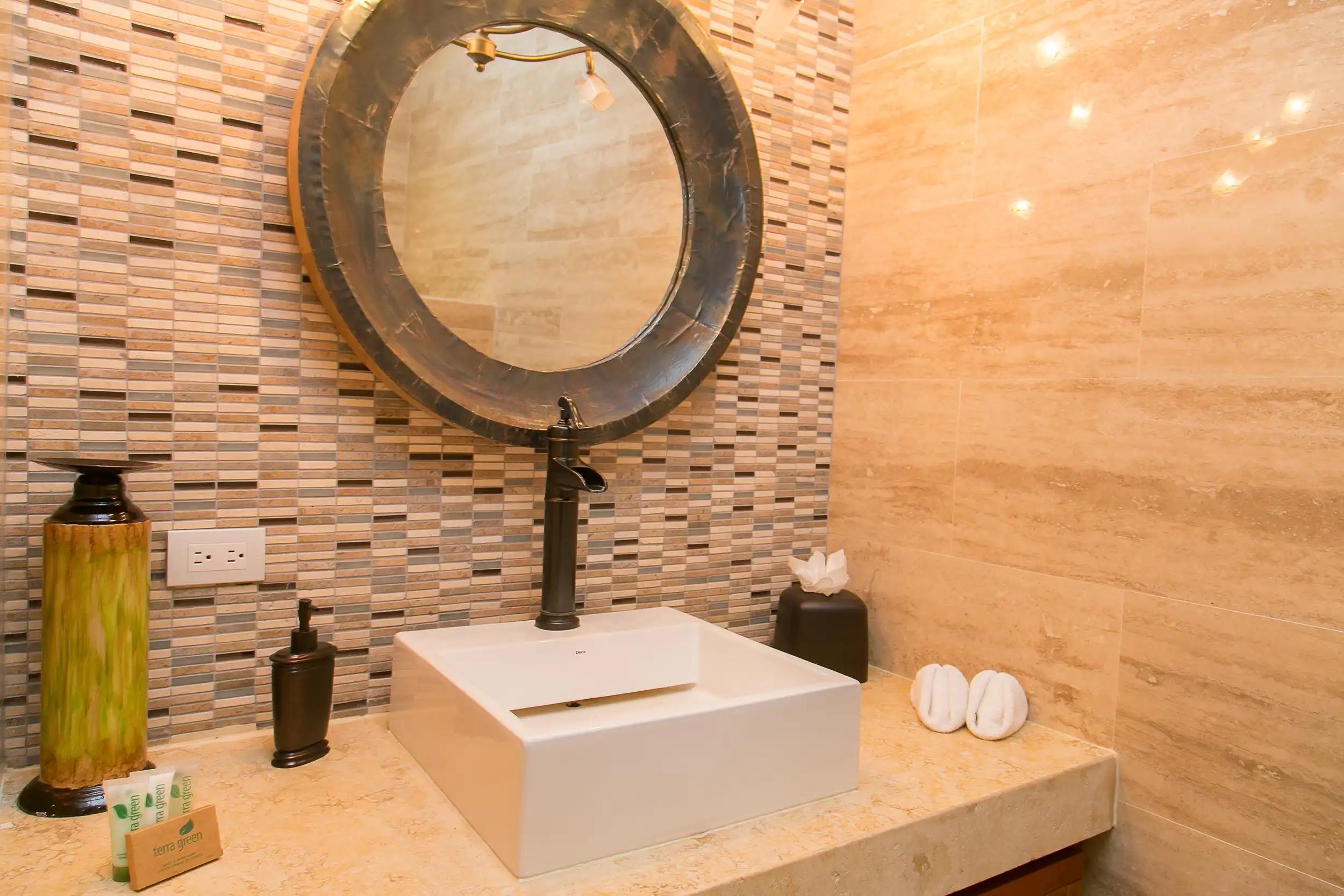 Square vessel sink beneath a round mirror in the Casa Anaka powder room