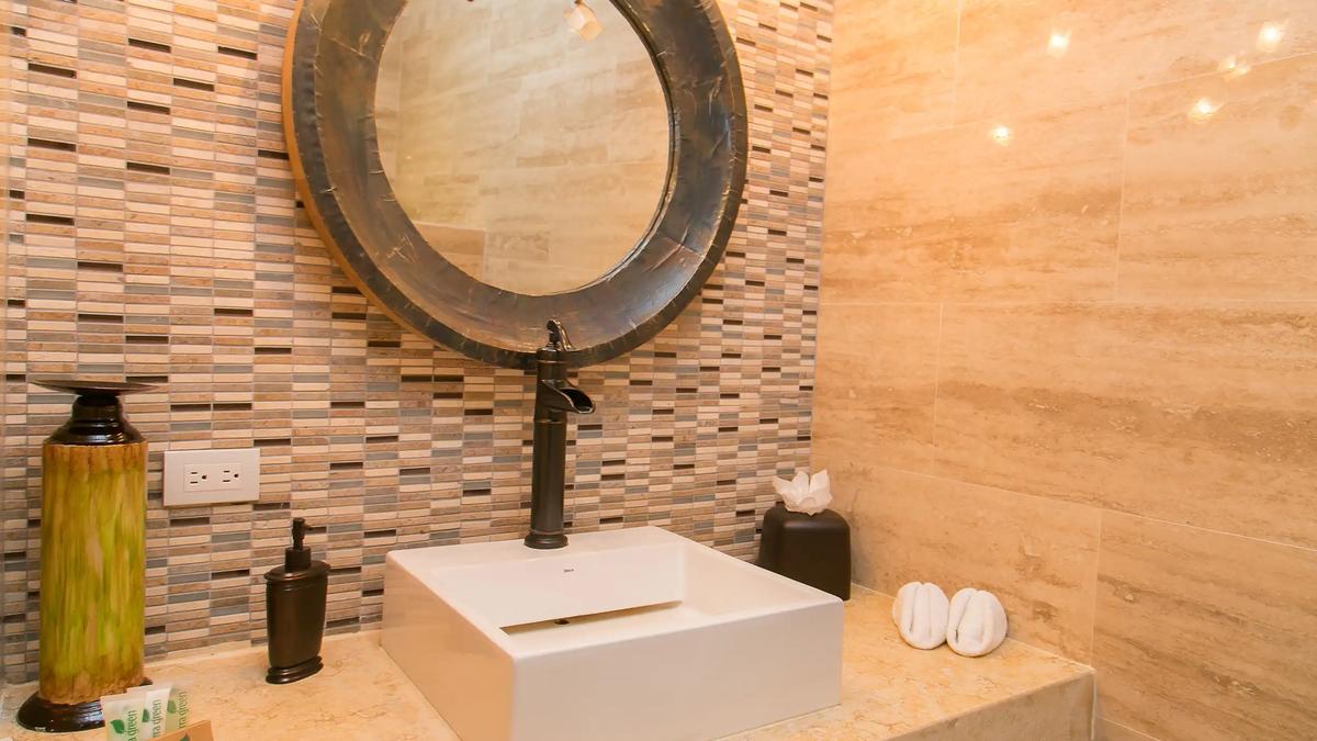 Square vessel sink beneath a round mirror in the Casa Anaka powder room