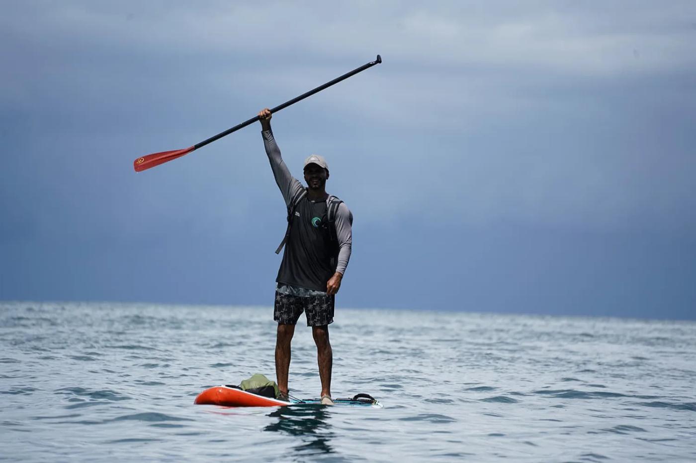 Paddleboarder raising a paddle against a grey sea sky