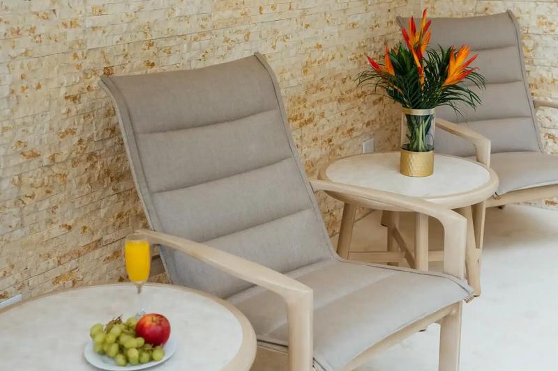 Patio lounge chairs at Casa Rambutan against a stone wall with fruit and mimosas